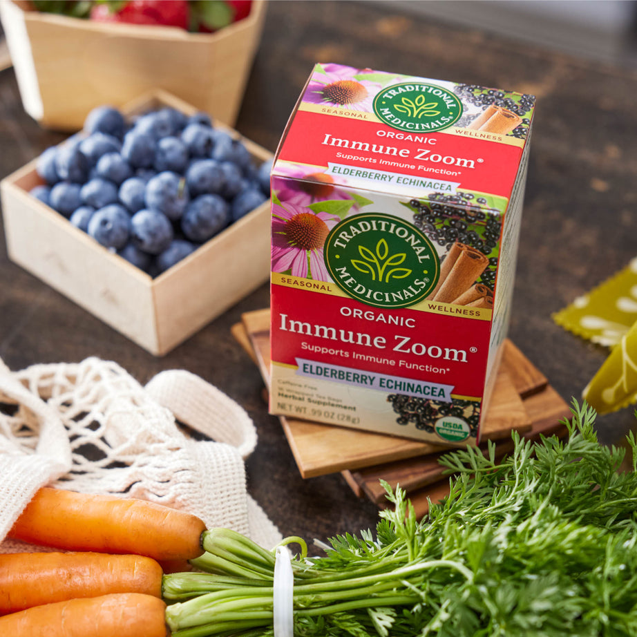 A box of Immune Zoom® Elderberry Echinacea Tea sits gracefully on a wooden table, offering a soothing blend that promotes immune support. View 2