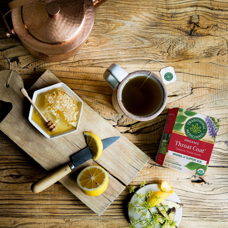 A cup of Throat Coat® Tea and lemon slices next to it